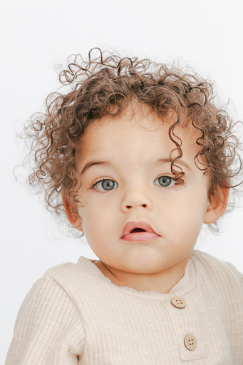 portrait of male toddler with curly hair on a white background
